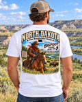 North Dakota Bigfoot shirt featuring Sasquatch riding a horse through the Badlands with bison and Roughrider State artwork.